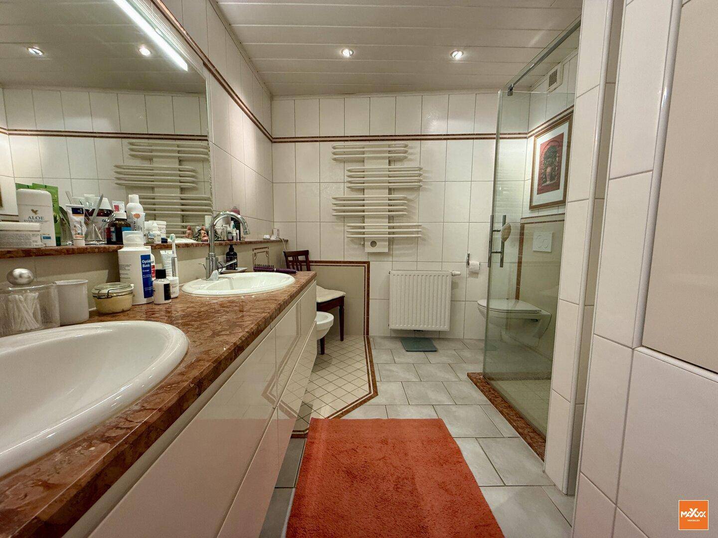 Geräumiges Badezimmer mit Doppelwaschbecken, Dusche und Fliesenboden.