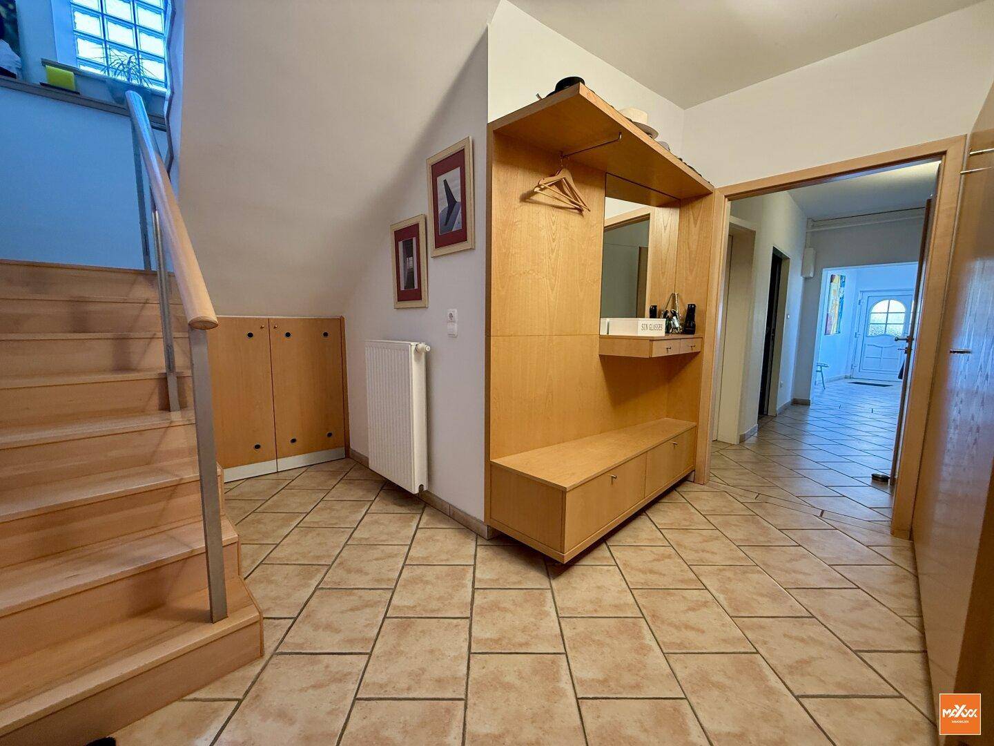 Eingangsbereich mit Fliesenboden, Garderobe und Holztreppe zum Obergeschoss.