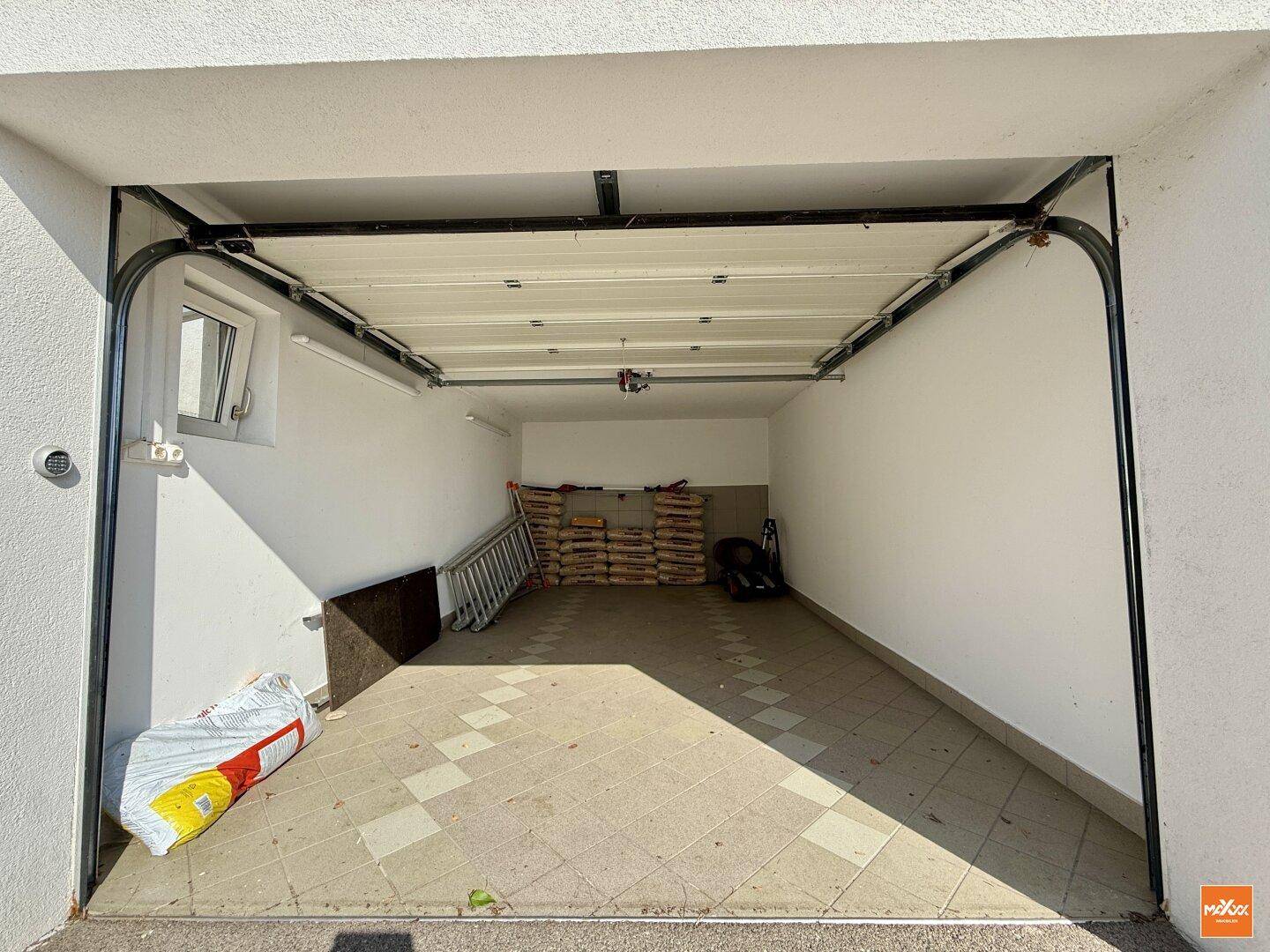 Einzelgarage mit Rolltor und Stauraum für Baumaterialien.