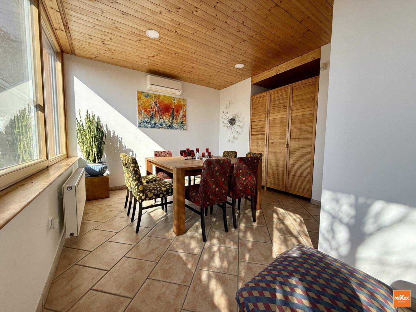 Heller Essbereich mit Holztisch, bunten Stühlen und Zugang zur Terrasse.