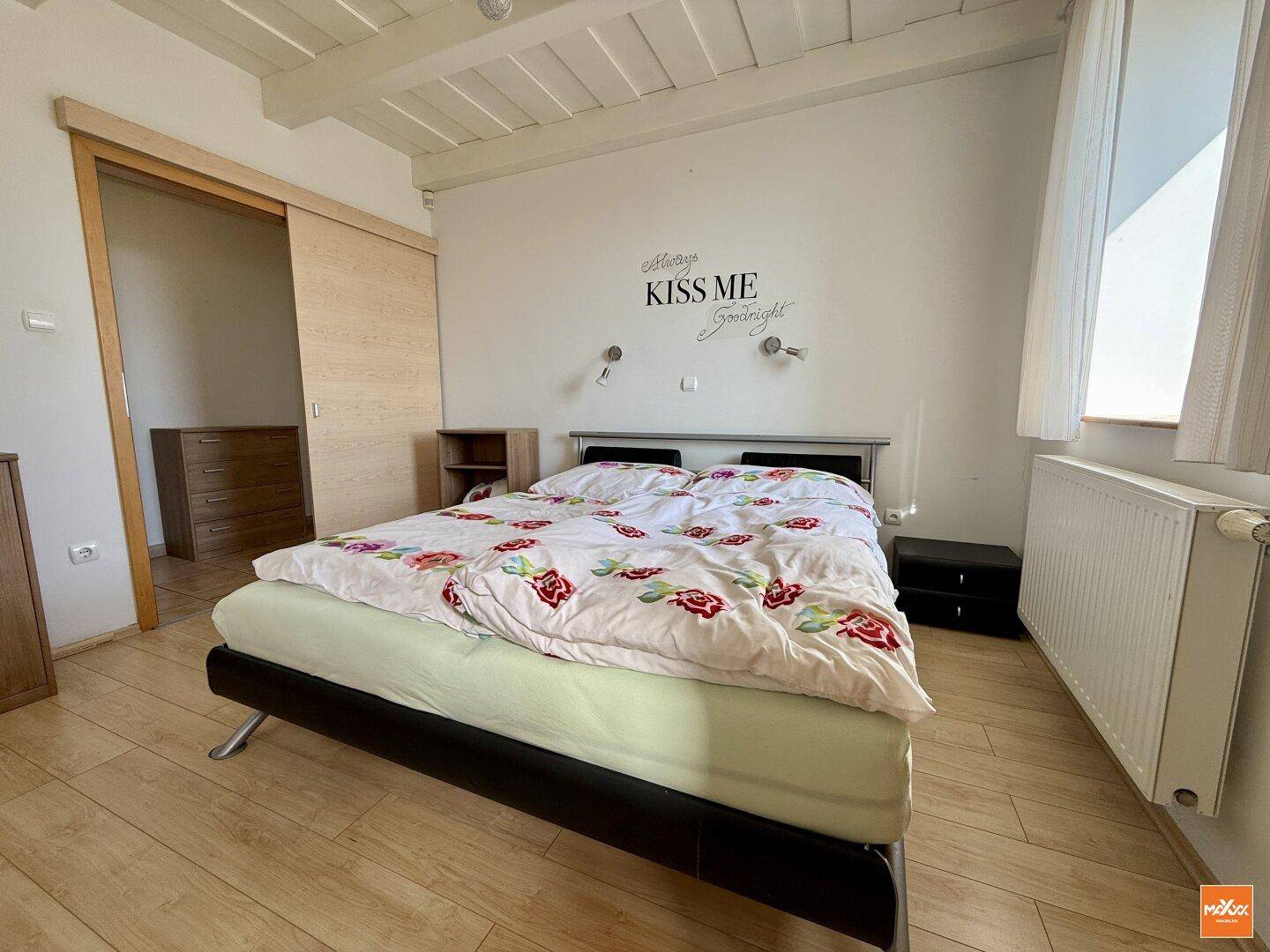 Gemütliches Schlafzimmer mit Doppelbett, Holzbalkendecke und hellem Holzboden.