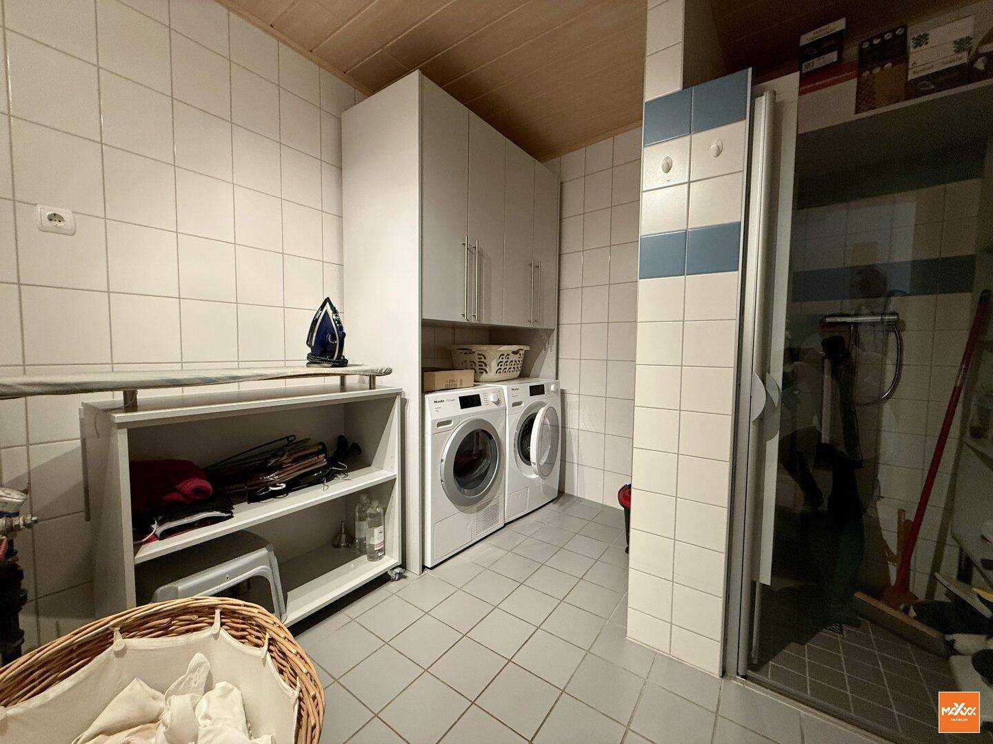 Waschküche mit Waschmaschine, Trockner und praktischen Regalen.