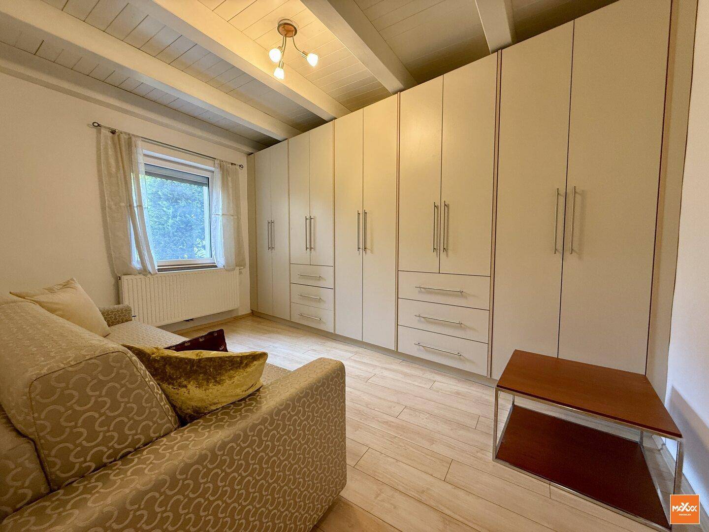 Schlafzimmer mit Einbauschränken, Holzbalkendecke und hellem Holzboden.