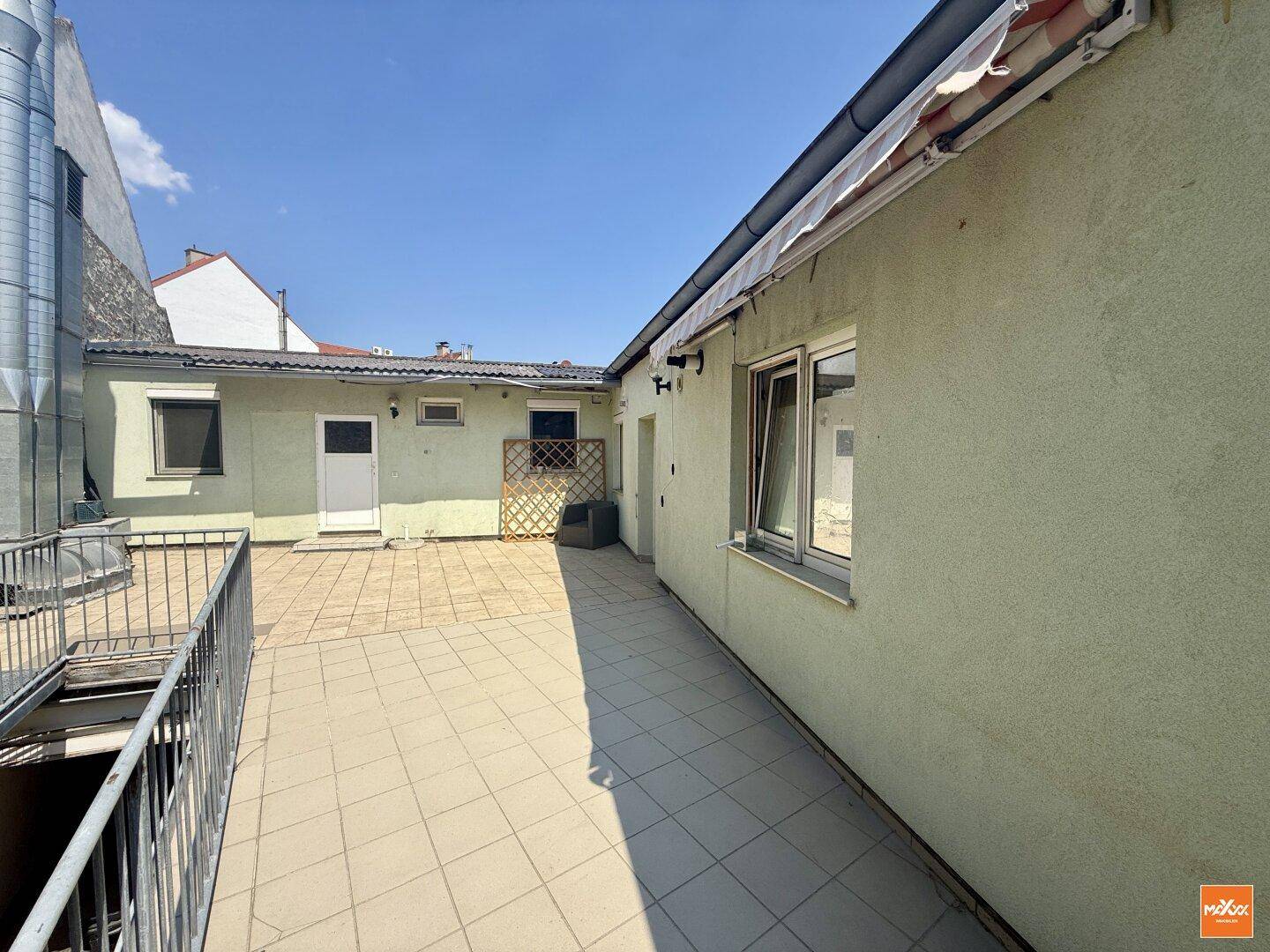 Gedeckte Terrasse mit Fliesenboden und Metallgeländer, ideal für entspannte Stunden im Freien.