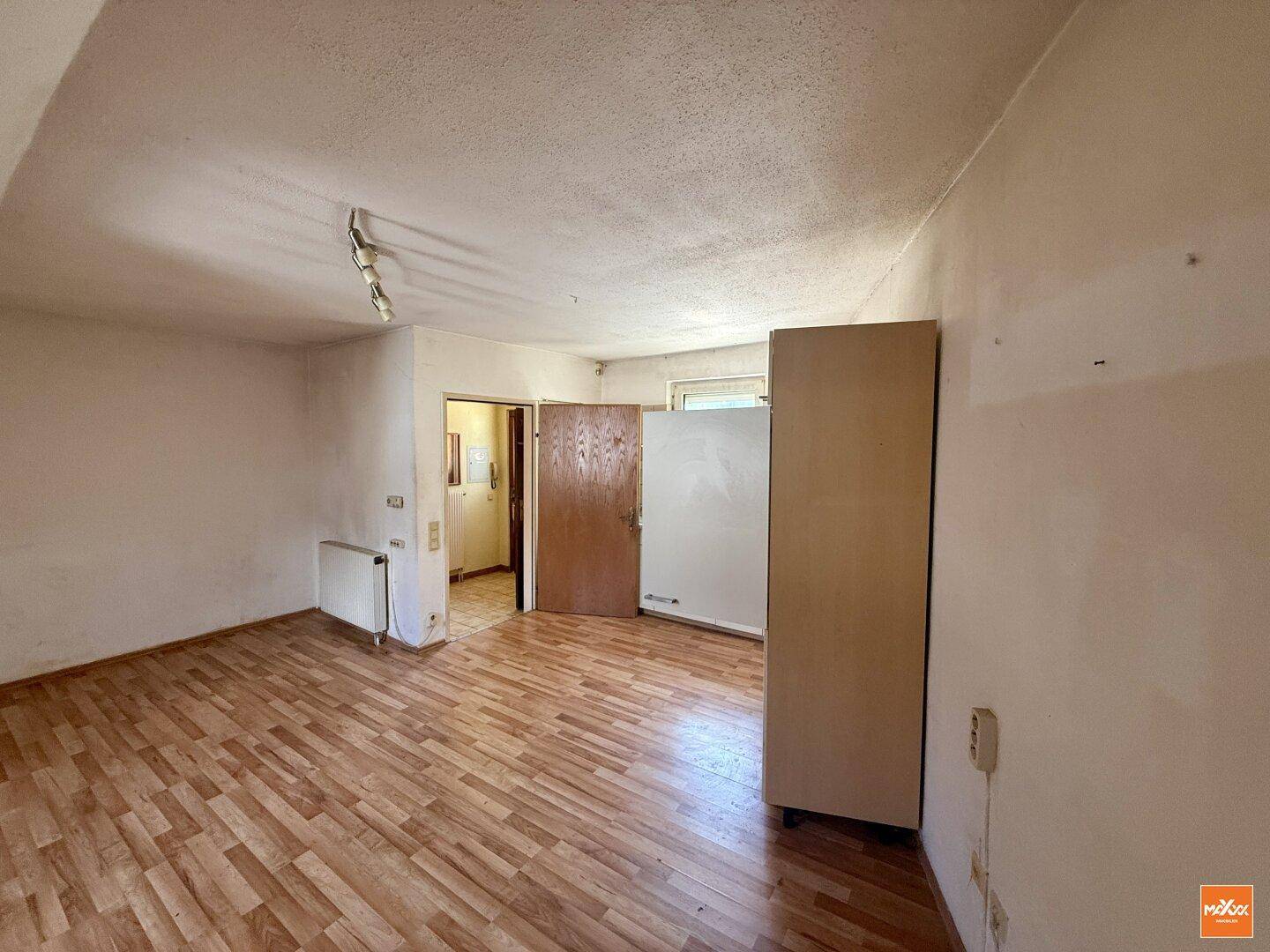 Geräumiger Wohnbereich mit Holzboden und Zugang zu weiteren Räumen, hell und funktional.