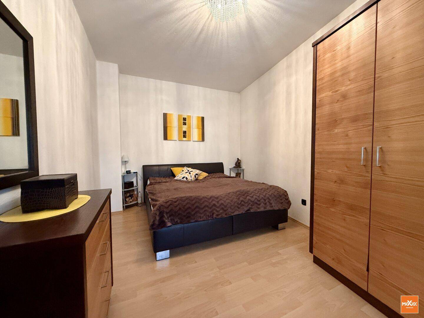 Schlafzimmer mit Doppelbett, Holzschrank und hellem Holzboden.