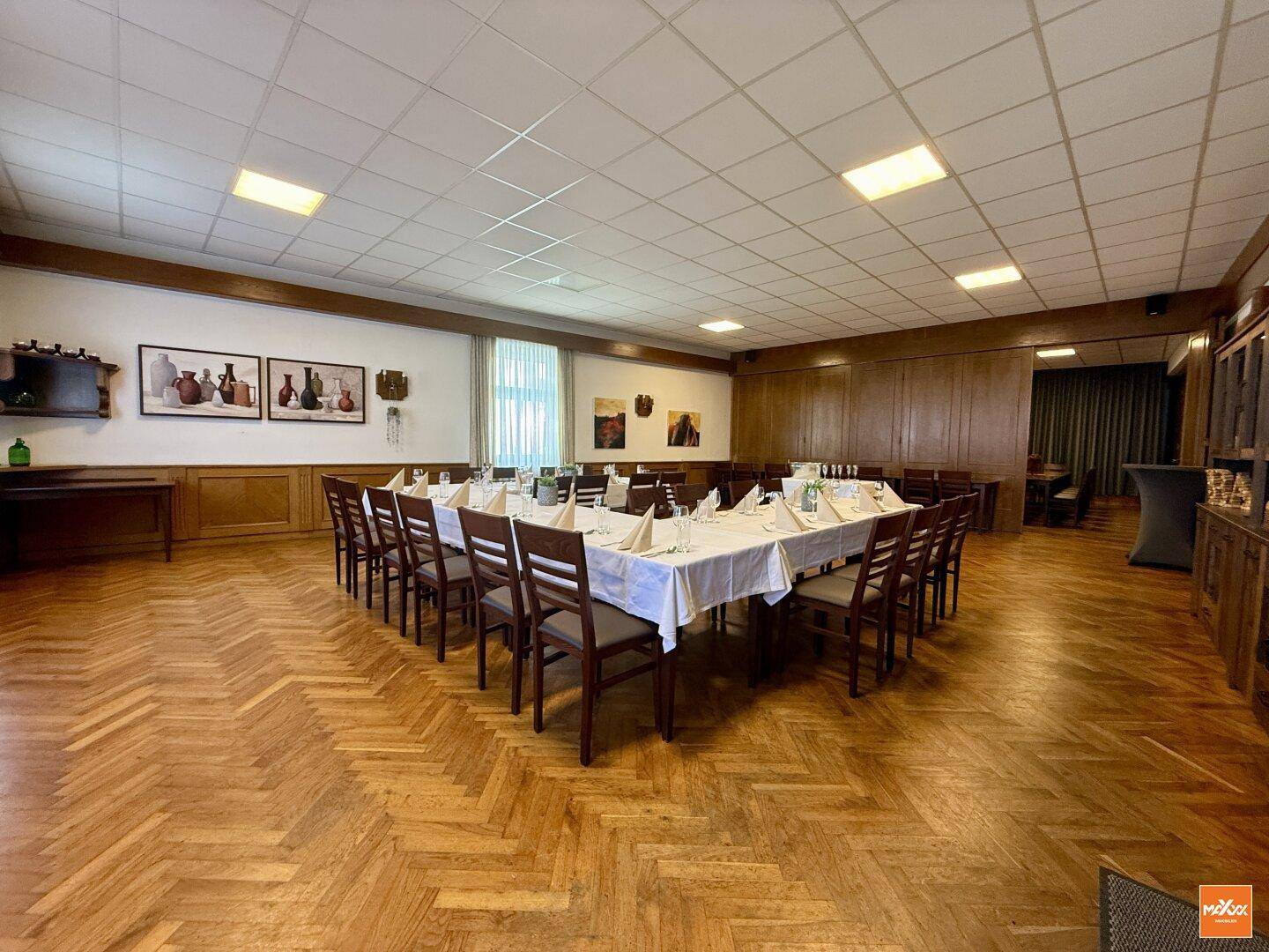 Großer Festsaal mit Fischgrätparkett, Holzwänden und festlich gedeckten Tischen.