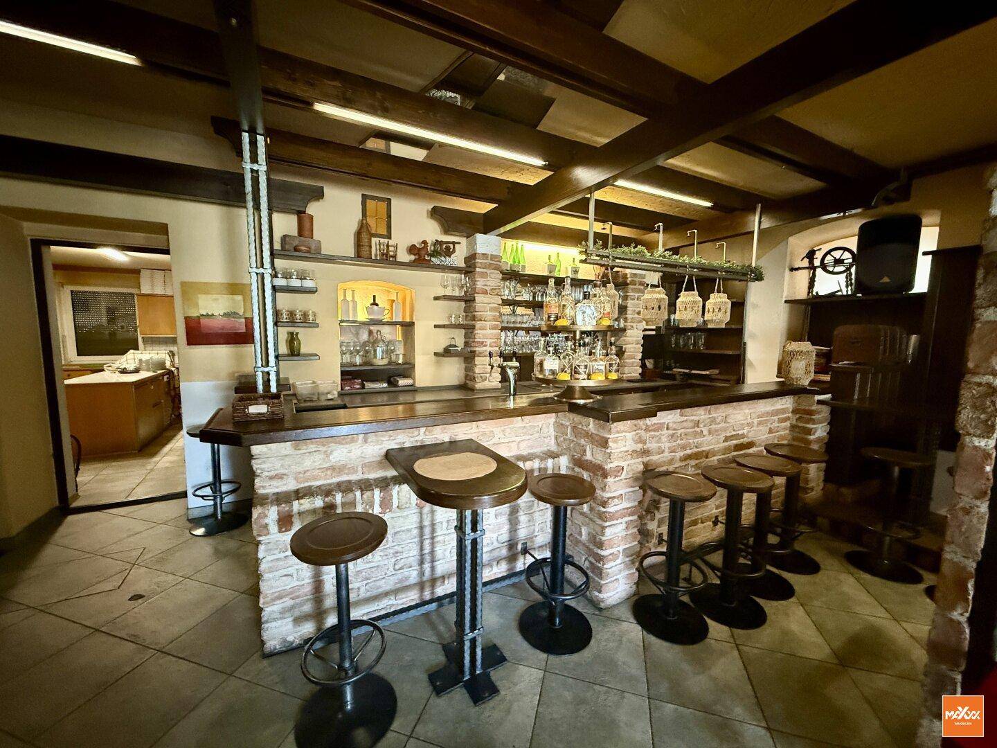 Rustikale Bar mit Ziegelmauerwerk, Holzbalken und Hockern in traditionellem Stil.