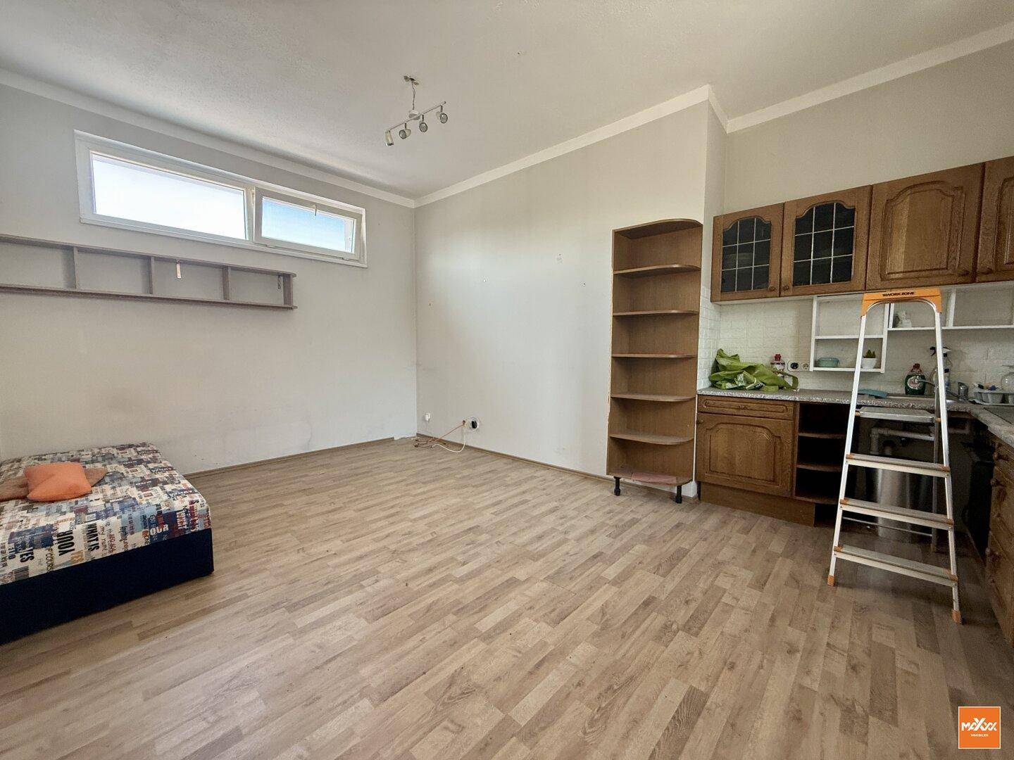 Wohnraum mit kleiner Küchenzeile, Bett und Laminatboden.