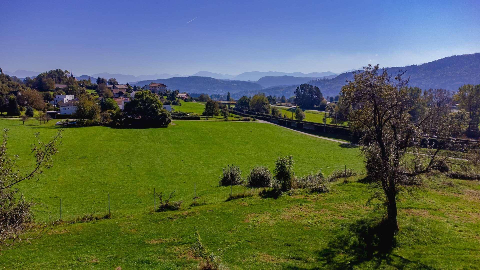 Idyllische ländliche Landschaft mit weiten grünen Feldern und Bergen am Horizont.