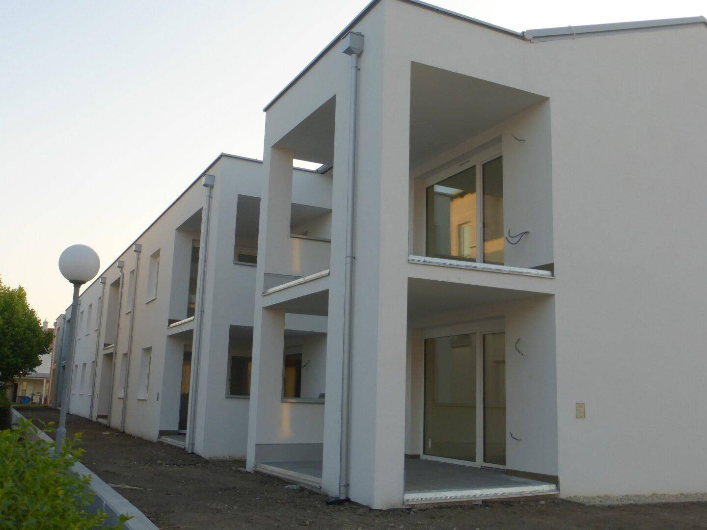 Moderne Gebäudefassade mit mehreren Loggien und großen Glasfronten, die viel Licht hereinlassen.