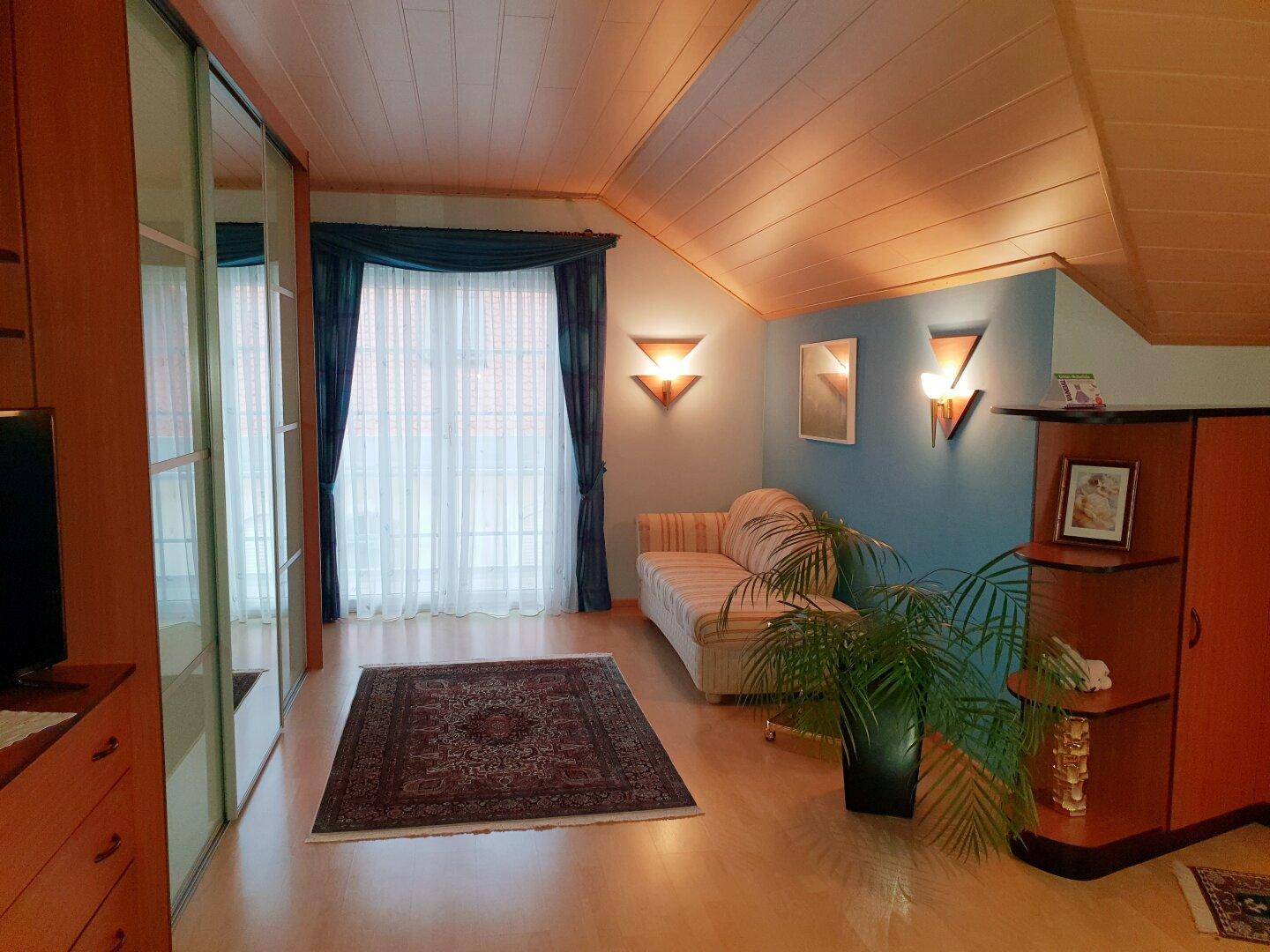 Gemütliches Wohnzimmer im Dachgeschoss mit Holzdecken, Parkettboden und großem Kleiderschrank.