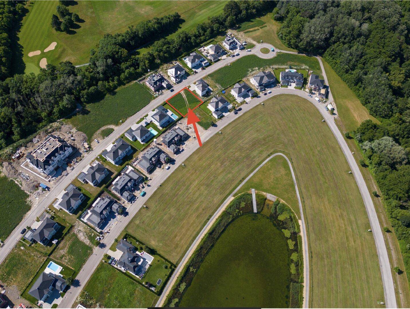 Luftaufnahme einer Wohnsiedlung mit Häusern, Grünflächen, einem Golfplatz und einem Teich.