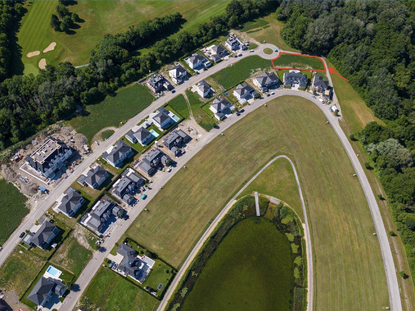 Luftaufnahme einer modernen Wohnsiedlung mit Häusern, Grünflächen und einem Golfplatz.