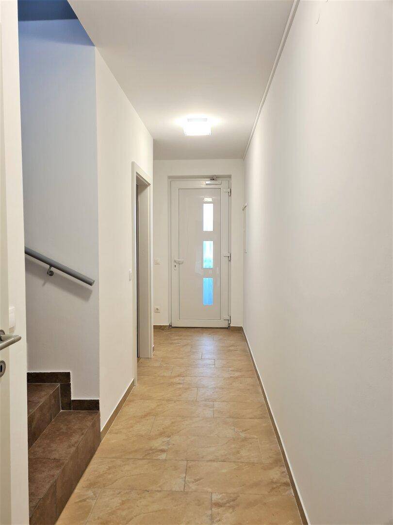 Heller Flur mit Fliesenboden und Zugang zu weiteren Räumen und Treppenhaus.