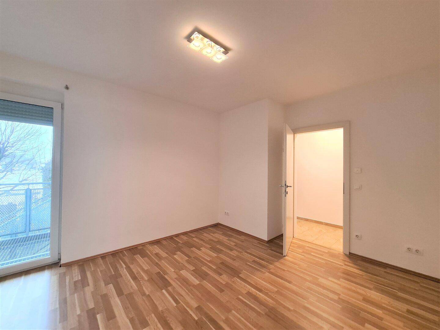 Helles Zimmer mit Parkettboden und Balkonzugang, ideal als Schlaf- oder Arbeitszimmer.