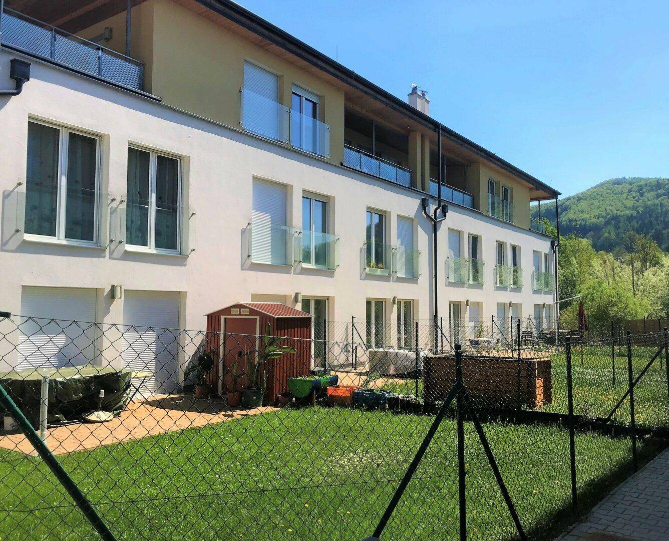 Rückseite des Wohngebäudes mit Gartenfläche, Zaun und Blick auf die umliegende Natur.