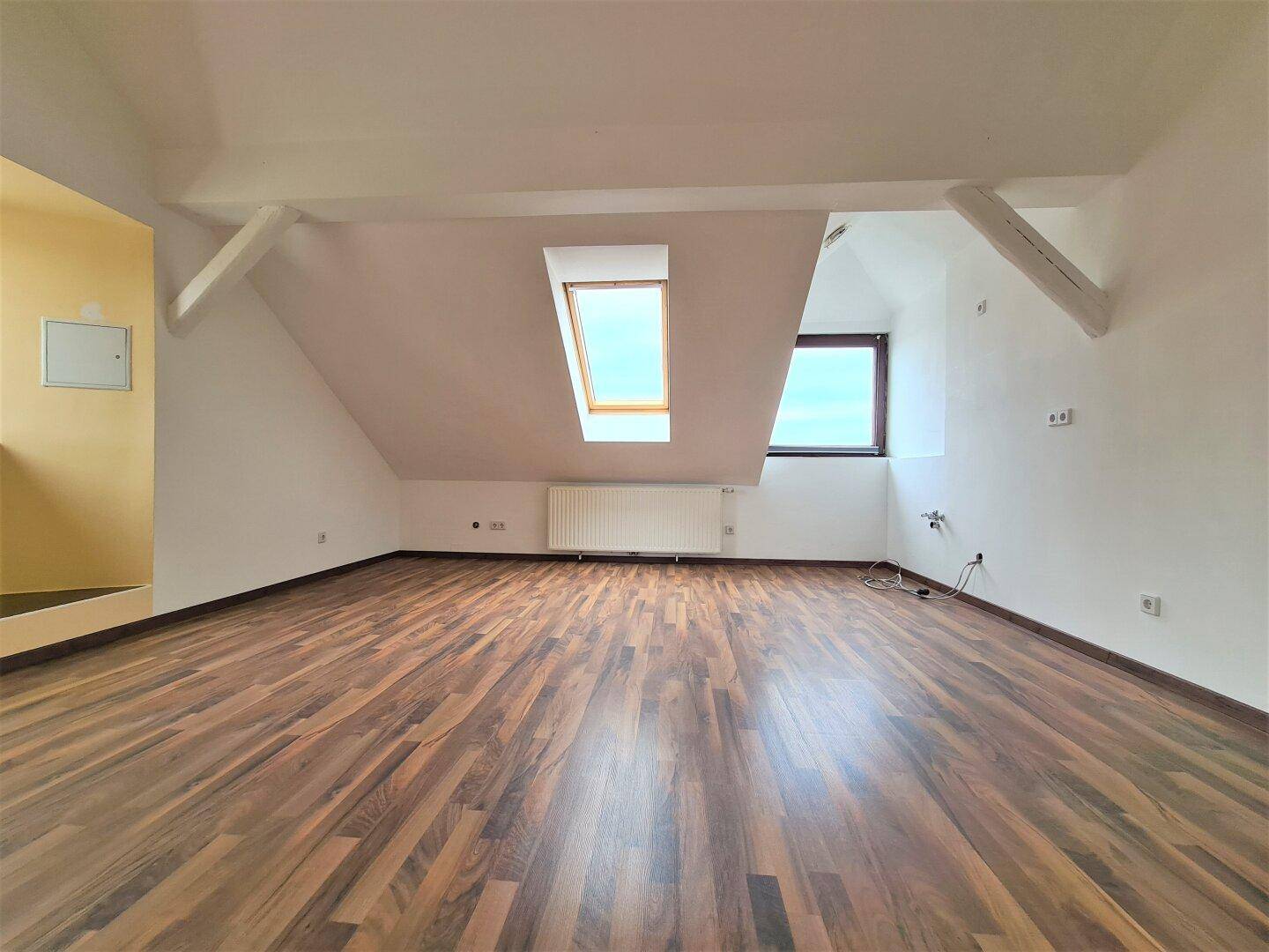 Geräumiger Dachbodenraum mit Laminatboden, schrägen Decken und mehreren Dachfenstern.