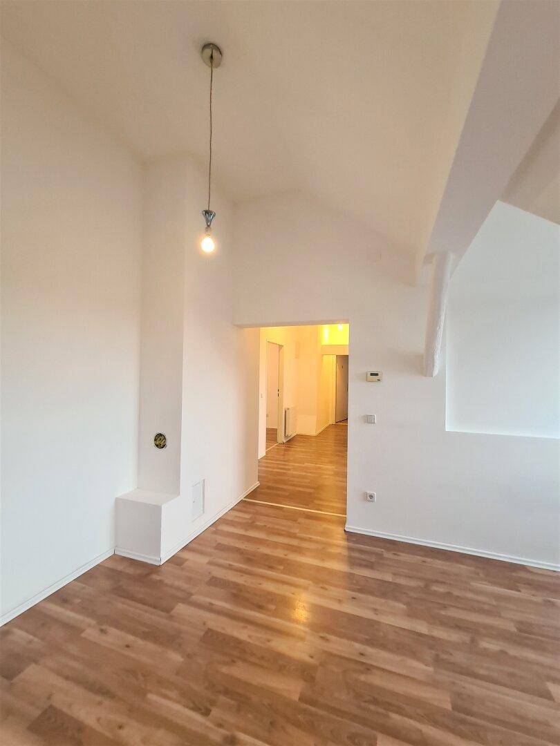 Heller Dachbodenraum mit Laminatboden, schrägen Decken und einem Zugang zum Flurbereich.