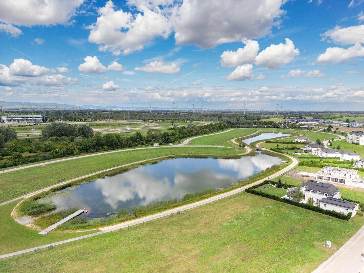 Weitläufige Luftaufnahme einer Landschaft mit Seen, Grünflächen und Wohngebäuden.