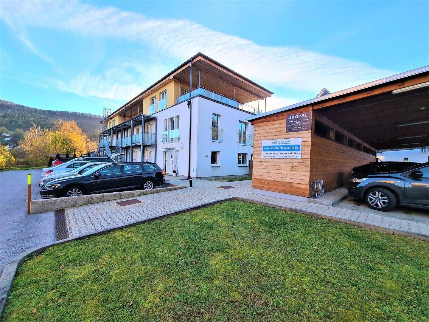 Modernes Wohngebäude mit Parkplätzen und Carports im Außenbereich.