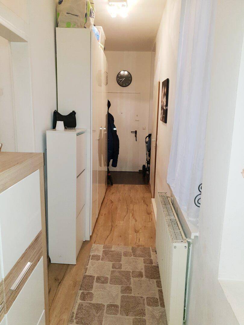 Langer Flur mit Garderobe, Schuhschrank und hellem Laminatboden.