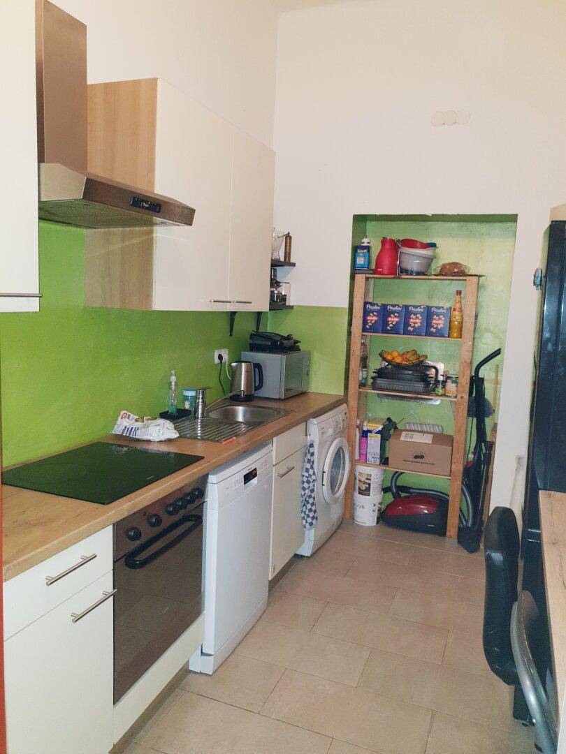Funktionale Küche mit grüner Wand, Holztheke und modernen Haushaltsgeräten.