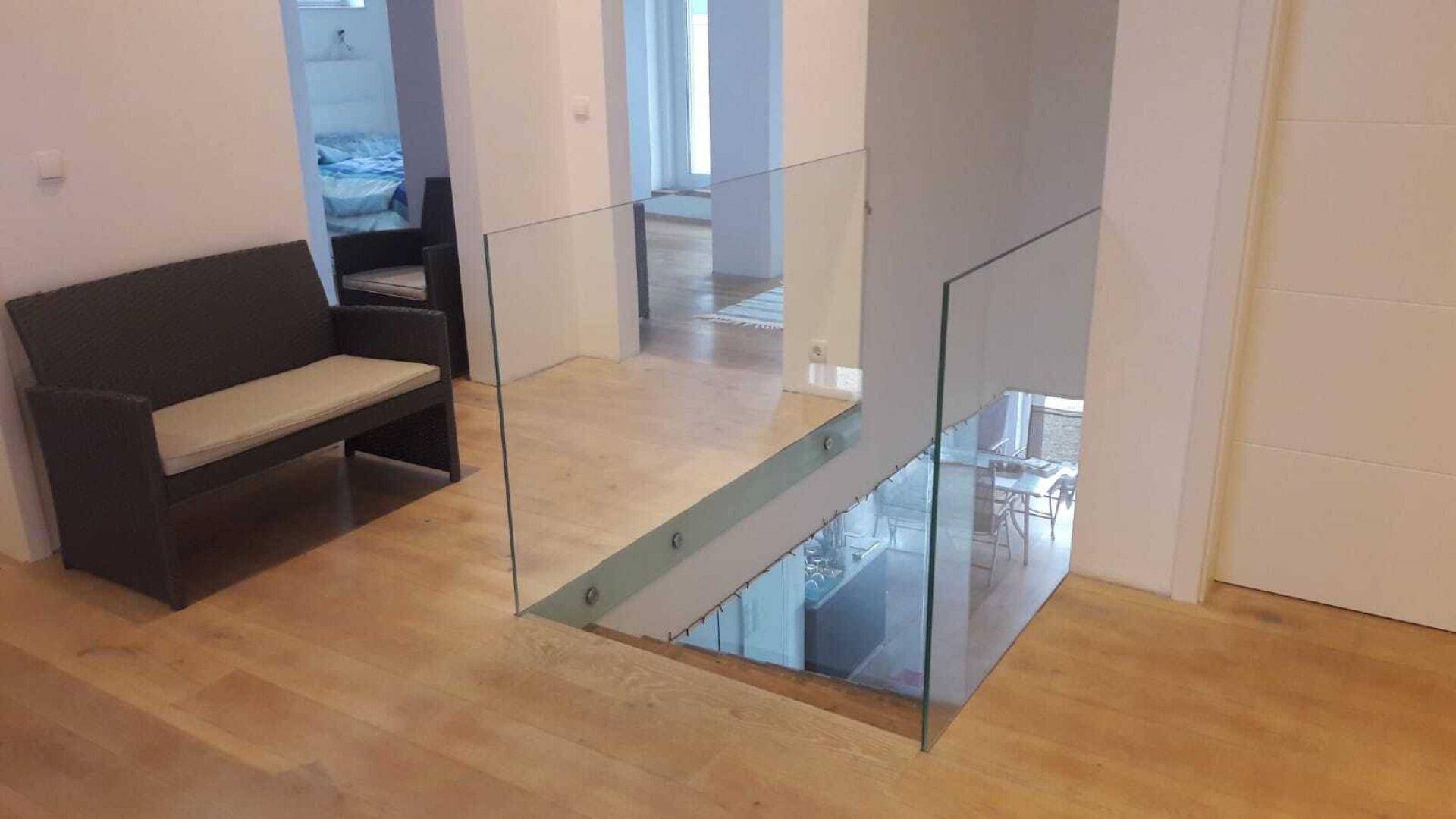 Offener Flur im Obergeschoss mit Glasgeländer und Blick auf die untere Etage.