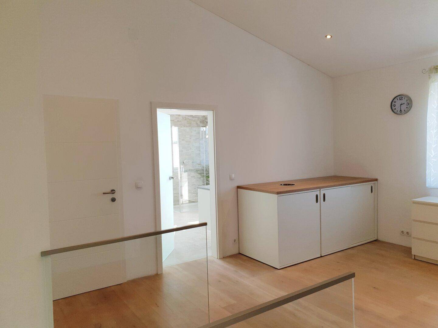 Heller Flur im Obergeschoss mit Einbauschrank und Blick in ein angrenzendes Badezimmer.