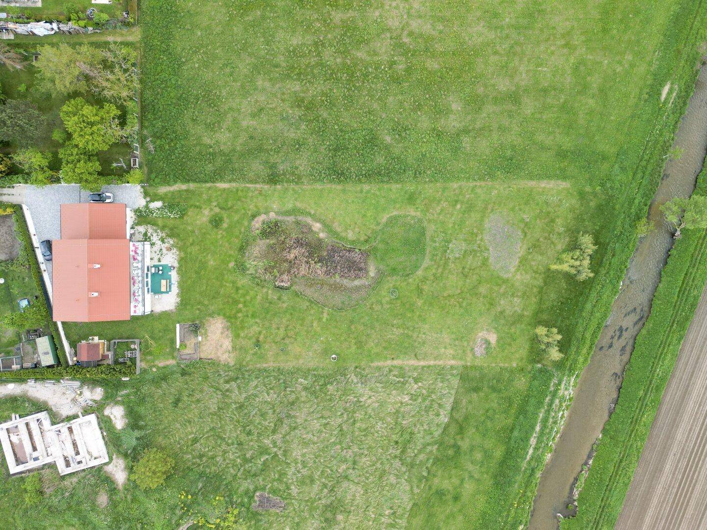 Vogelperspektive des Anwesens mit Haus, Teich und weitläufigen grünen Feldern.