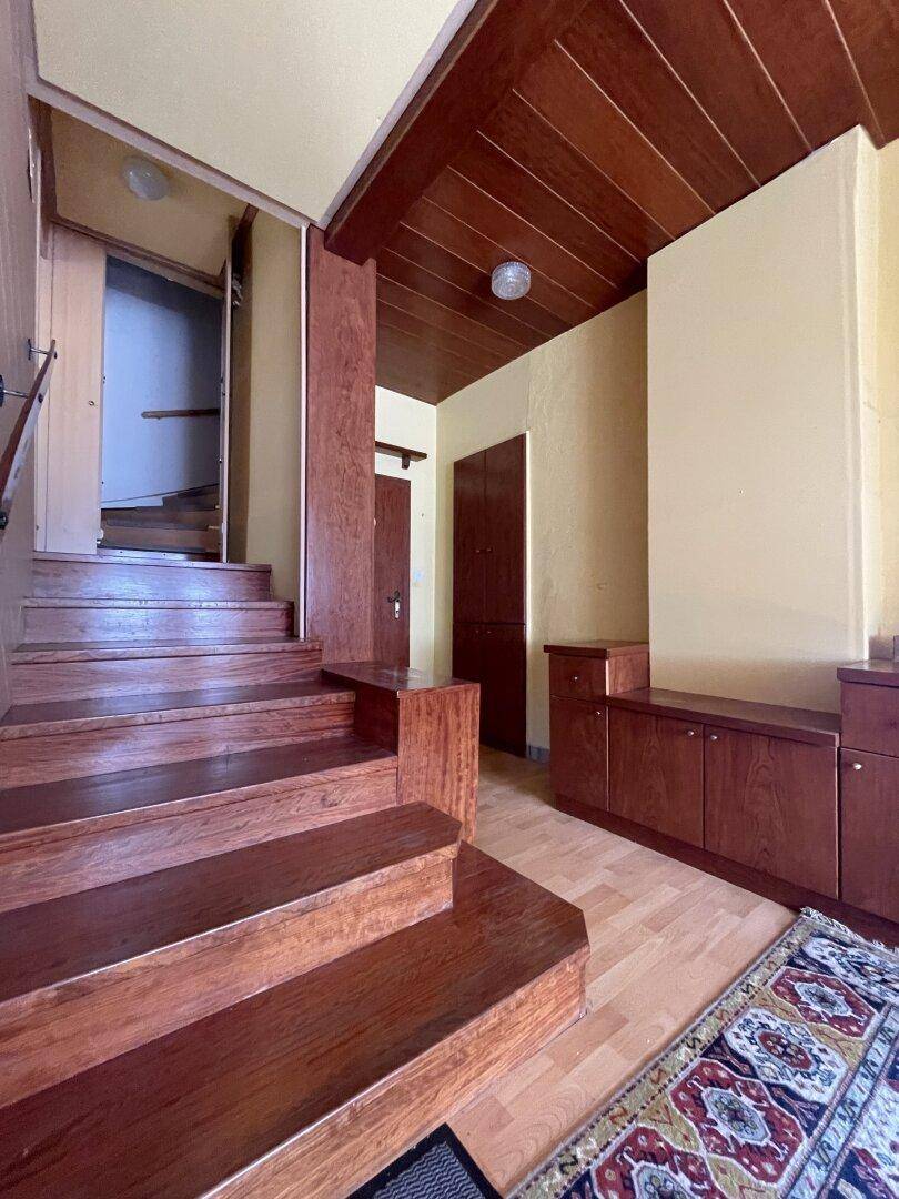 Geräumiger Eingangsbereich mit Holztreppe und passenden Holzvertäfelungen an Decke und Wänden.