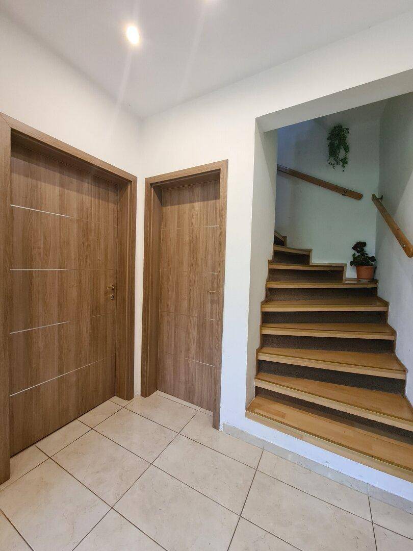 Heller Flur mit Holztreppe und modernen Holztüren.