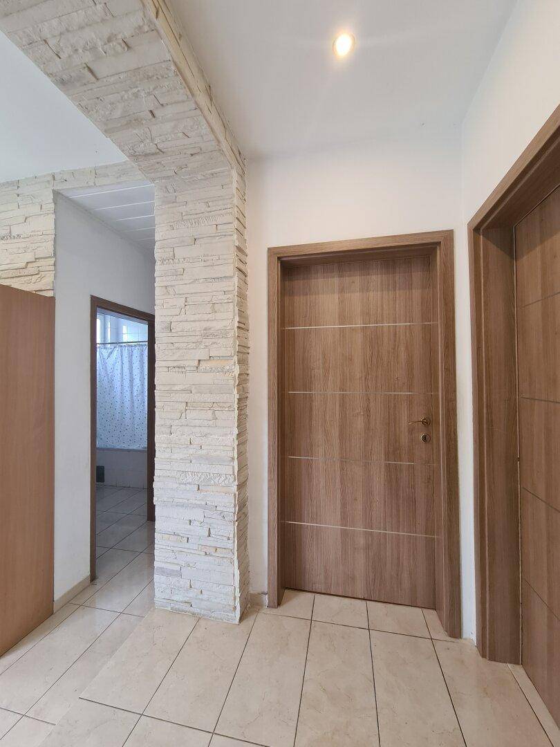 Flur mit dekorativer Steinwand und Holztüren, die zu weiteren Räumen führen.