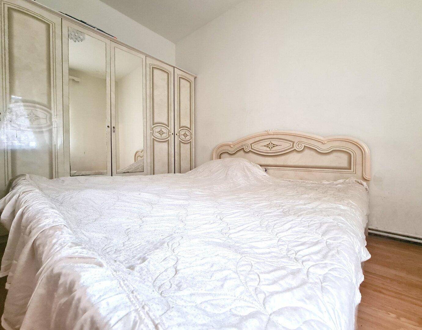 Schlafzimmer mit großem Bett, weißer Bettwäsche und einem Spiegelschrank.