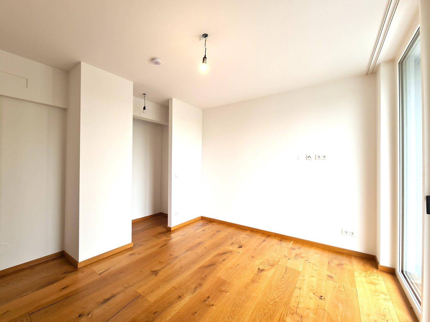 Heller Raum mit Holzboden und großen Fenstern, bereit für individuelle Gestaltung.