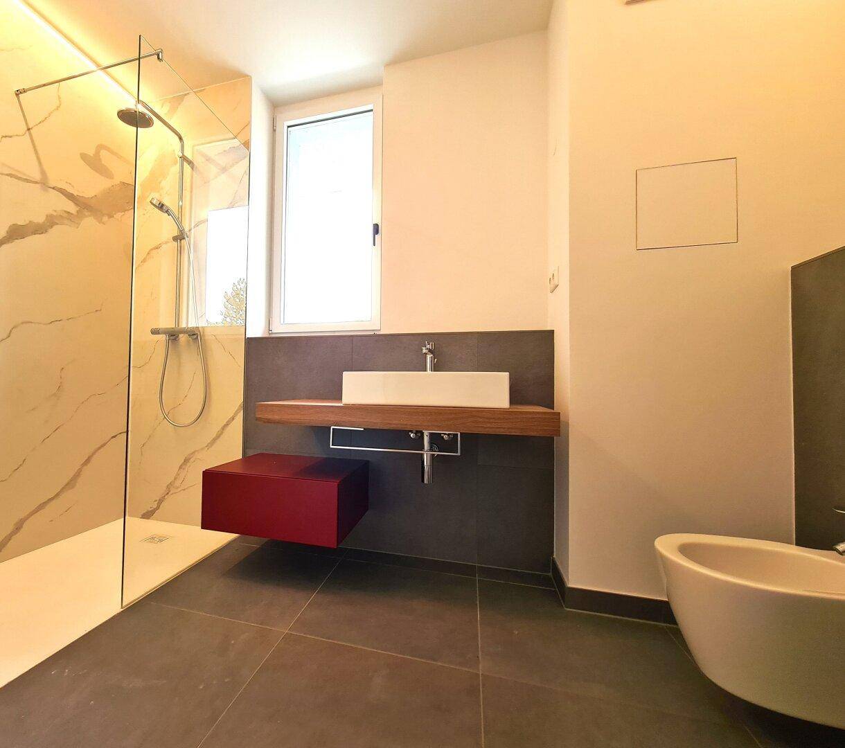 Modernes Badezimmer mit ebenerdiger Dusche, Waschtisch und Bidet, hell und funktional.