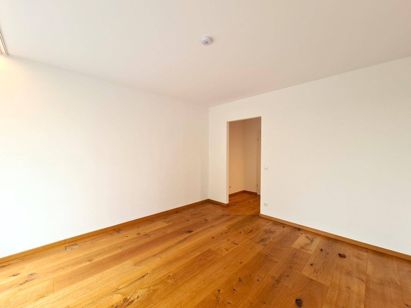 Leerer Raum mit Holzboden und weiß gestrichenen Wänden, ideal für verschiedene Nutzungen.
