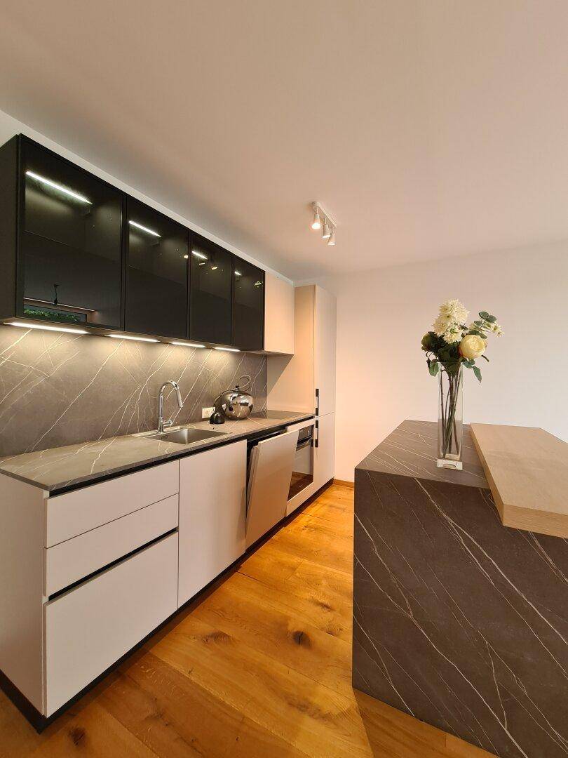 Moderne Einbauküche mit dunklen Oberschränken, integriertem Geschirrspüler und Holzboden.