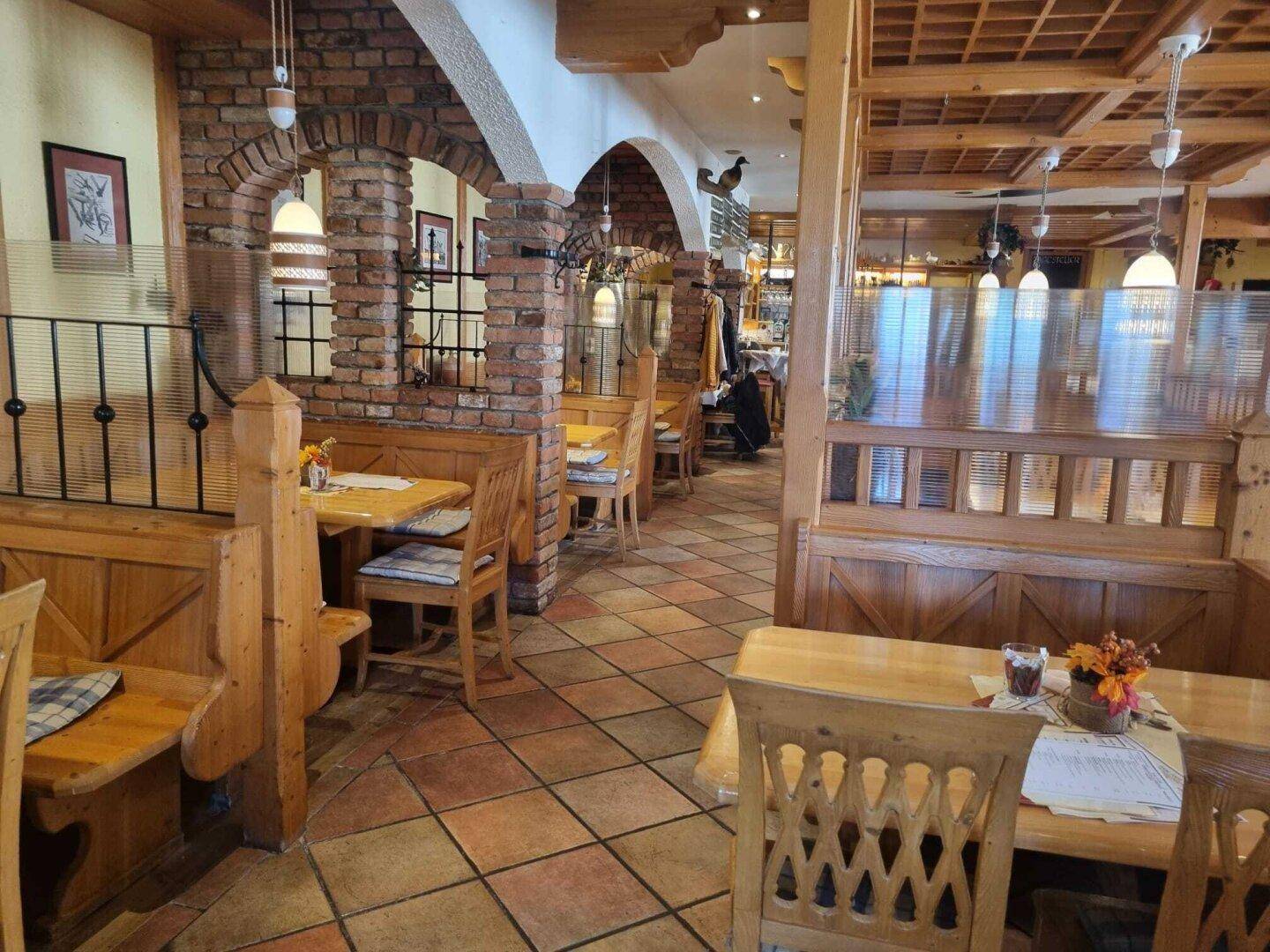 Gemütlicher Restaurantbereich mit Holzbänken, Ziegelbögen und traditionellen Fliesenböden.