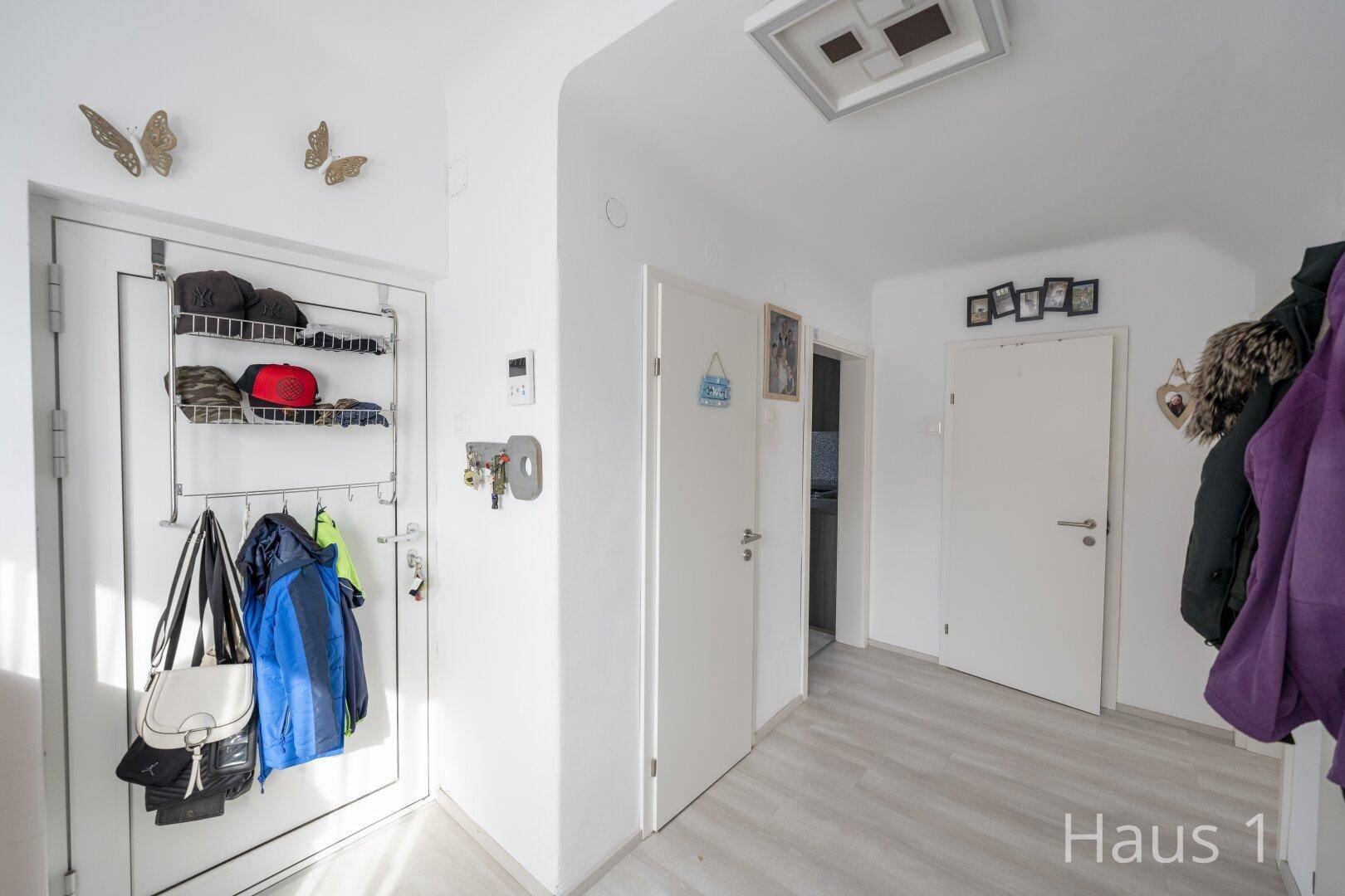 Heller Eingangsbereich mit Garderobe an der Tür und weiß gestrichenen Wänden.