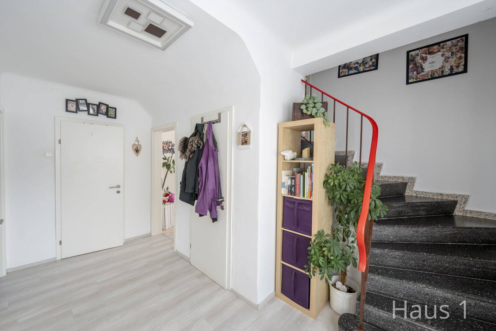Geräumiger Flur mit Treppe, Bücherregal und Garderobe, hell und freundlich gestaltet.