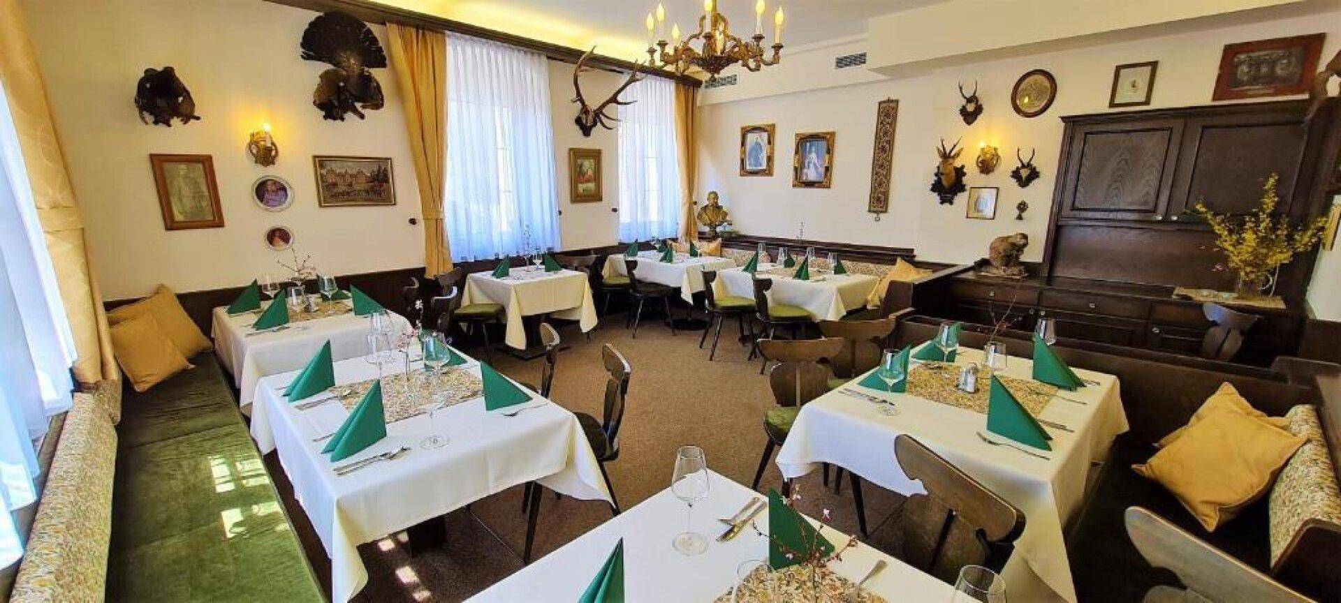 Gemütlicher Speisesaal mit traditioneller Jagddekoration und festlich gedeckten Tischen.