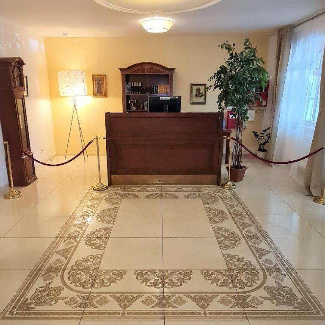 Empfangsbereich des Hotels mit einer Holzrezeption, gemusterten Fliesen und traditionellen Möbeln.