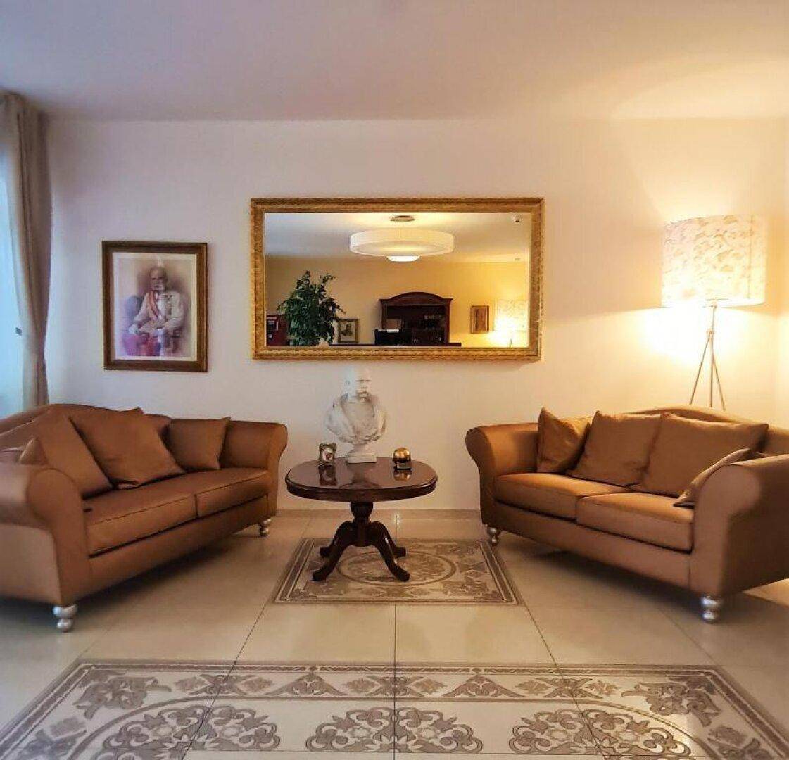 Gemütlicher Loungebereich mit zwei braunen Sofas, einem Couchtisch und einem großen Spiegel.