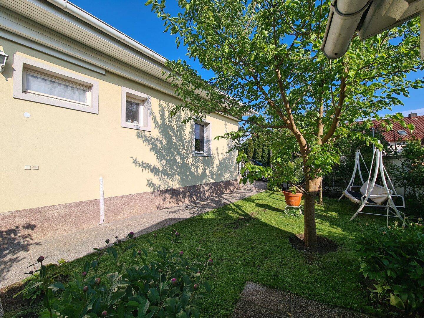 Seitenansicht des Hauses mit Gartenbereich, Schaukel und viel Grün.