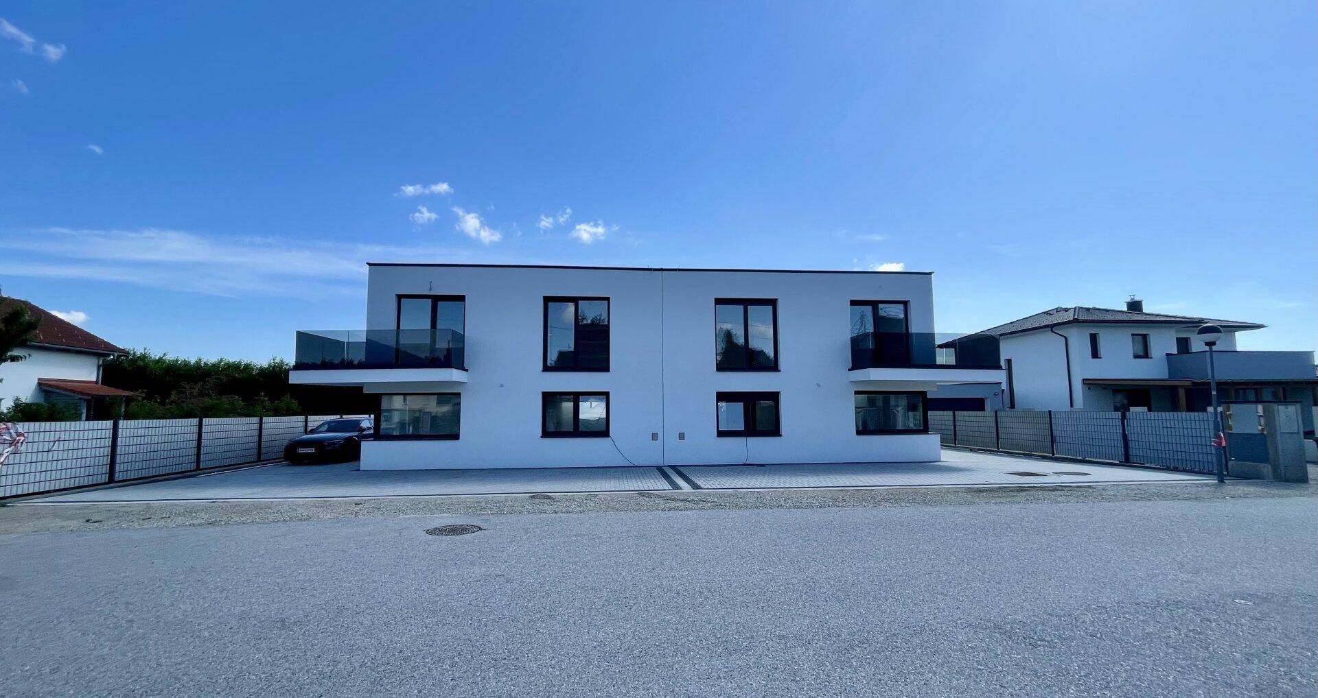 Ansicht der modernen Doppelhaushälfte von der Straße mit klarem Himmel.