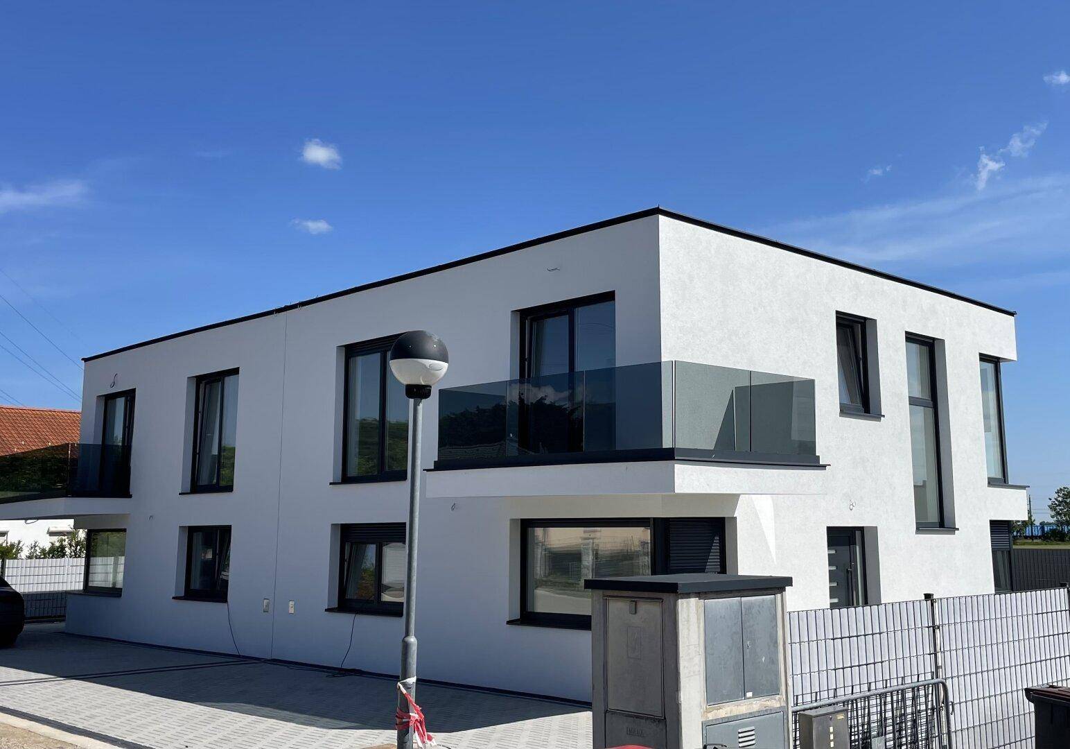 Schräge Ansicht der Doppelhaushälfte mit moderner Architektur und klarem Himmel.