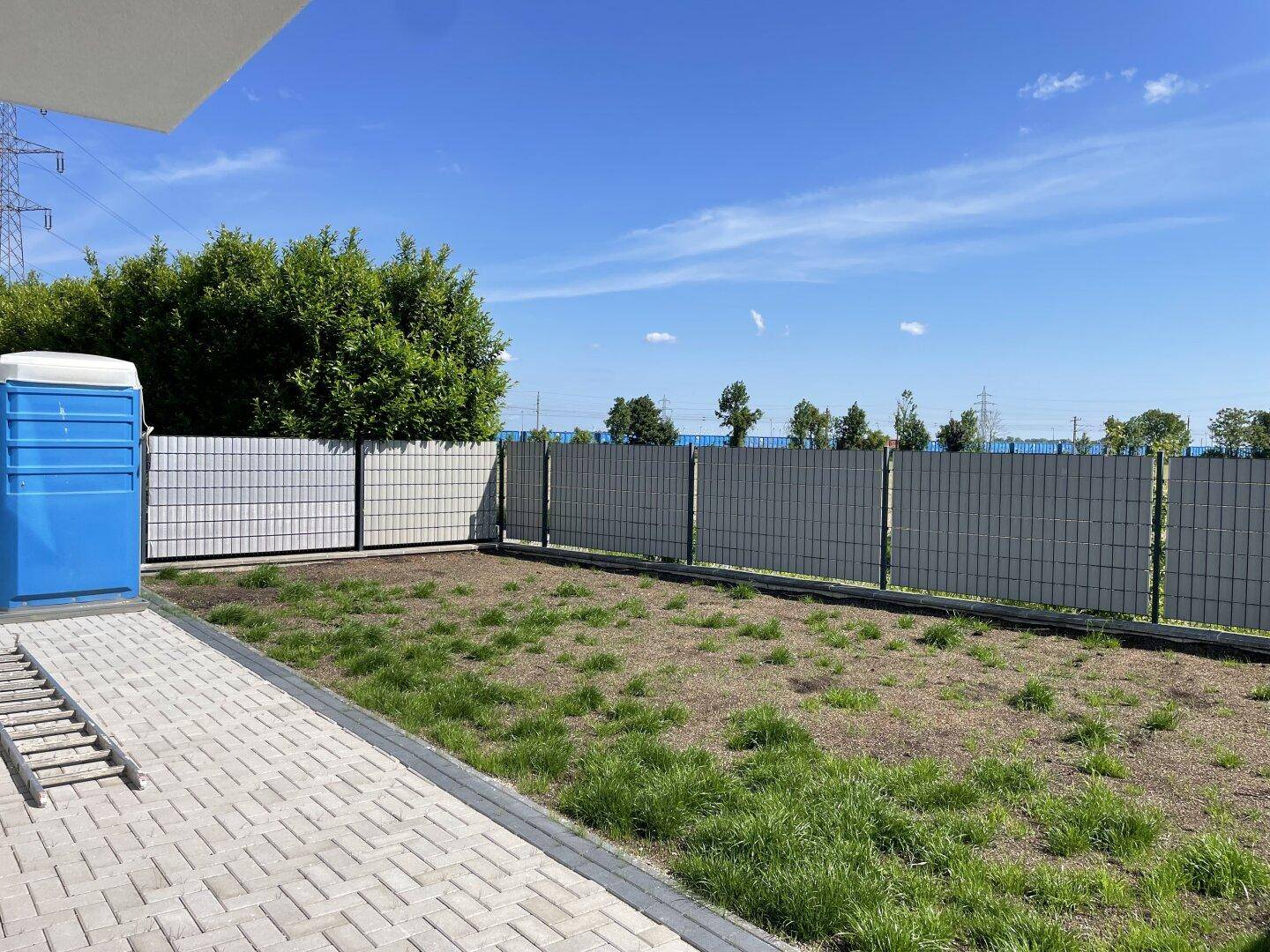Unfertiger Gartenbereich hinter der Doppelhaushälfte mit Zaun und Blick ins Grüne.