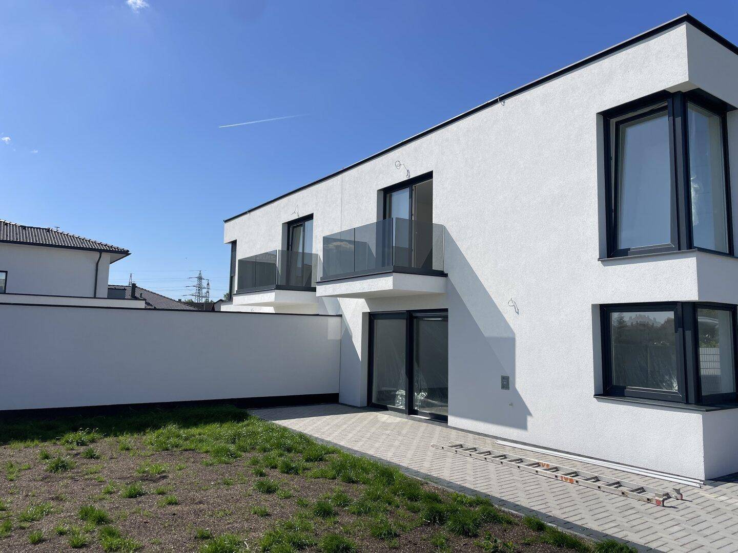 Seitenansicht der Doppelhaushälfte mit Gartenbereich und gepflastertem Zugang.