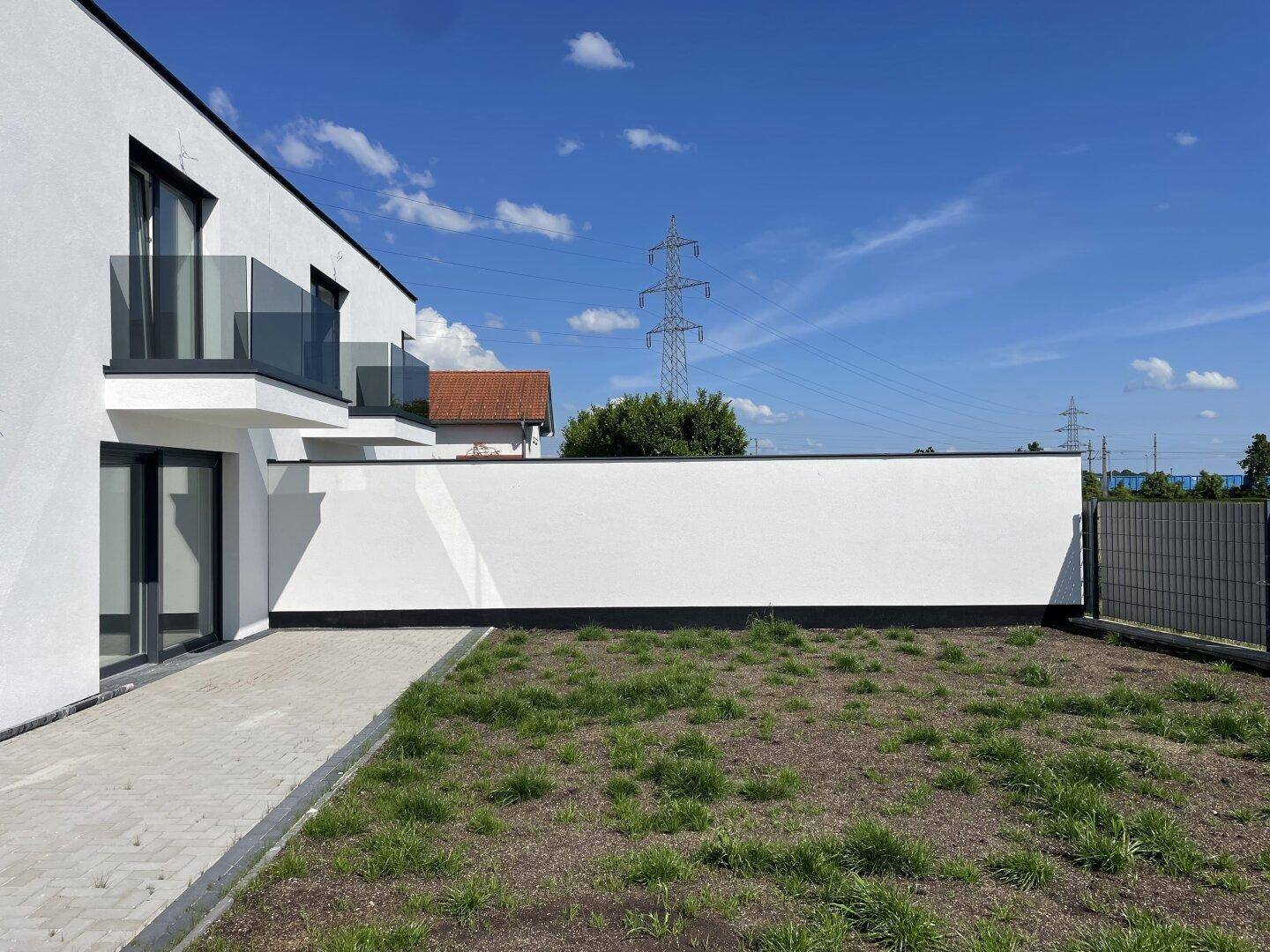 Gartenbereich hinter der Doppelhaushälfte mit hoher Mauer und Blick auf die Landschaft.
